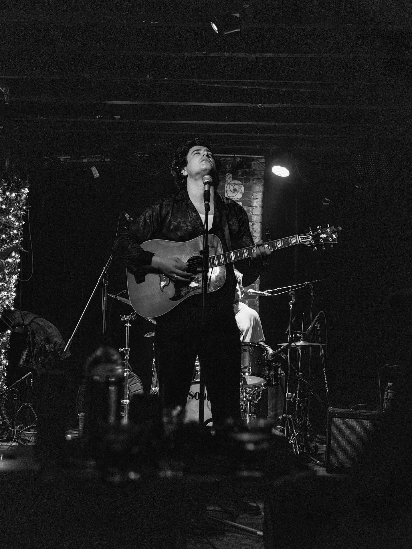 Joey Myron singing on stage under a single light