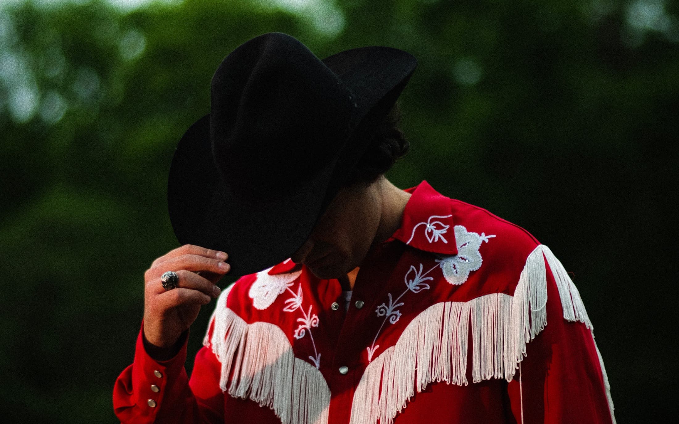 Joey Myron in a red embroidered fringe shirt and black hat